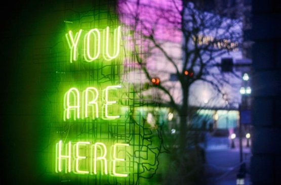 wdys 24 the picture shows a neon sign with the words You Are Here in the background a view of city lights