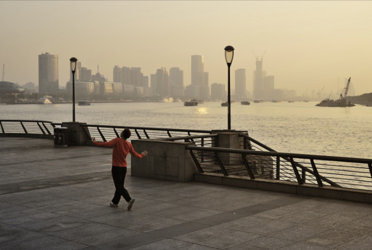 Tthe photo shows a man, on a pier, in a carefree swinging movement. A body of water is visible in the background.