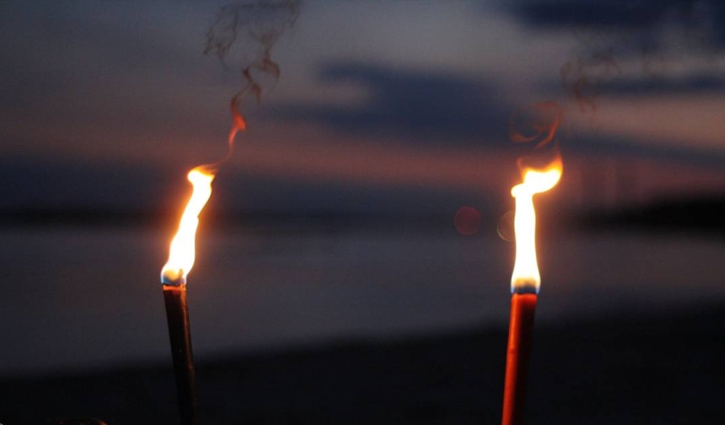 Two torches shining in the darkness with water in the backgrond